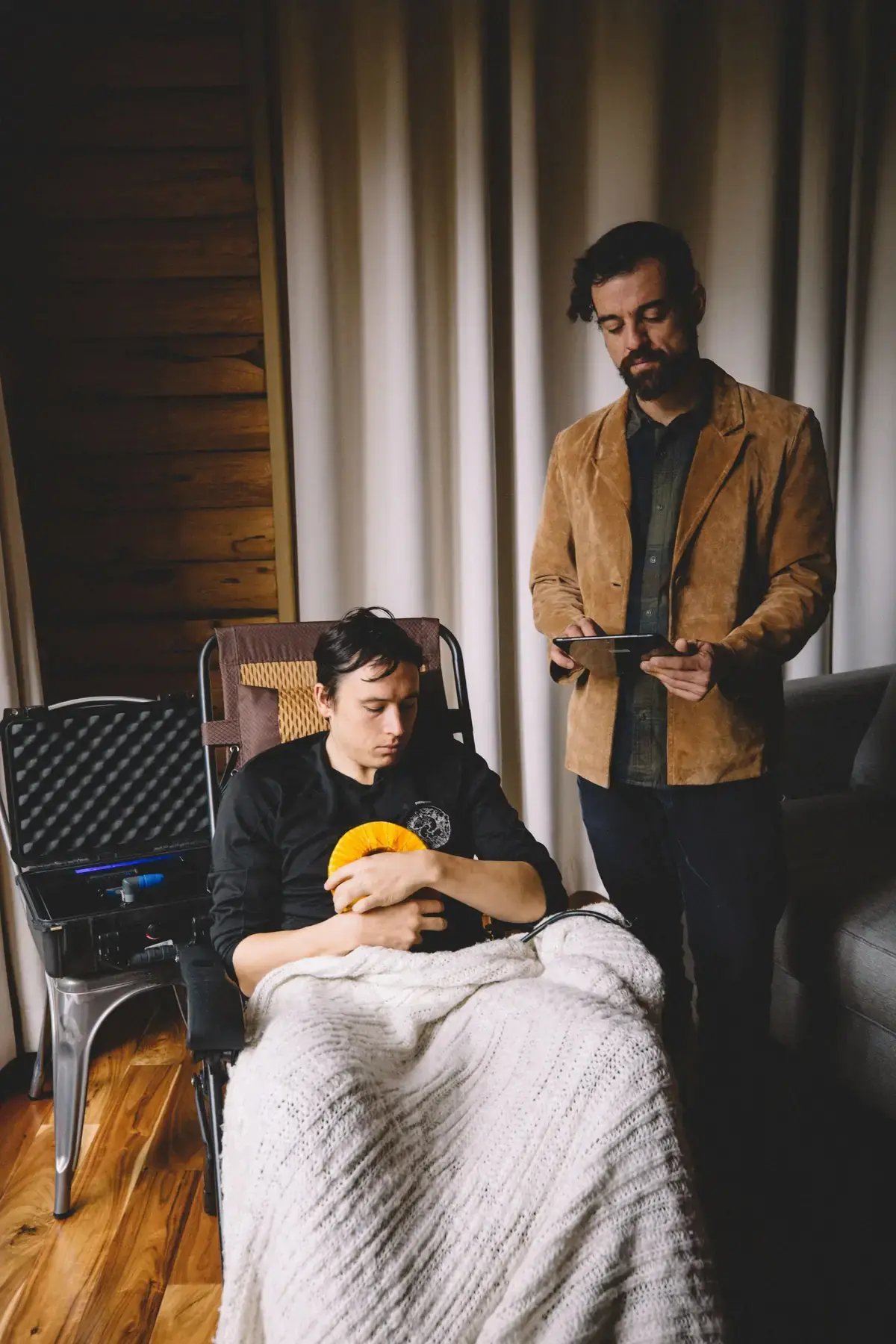 Practitioner holding a tablet while a client rests in a recliner with the AmpCoil coil
