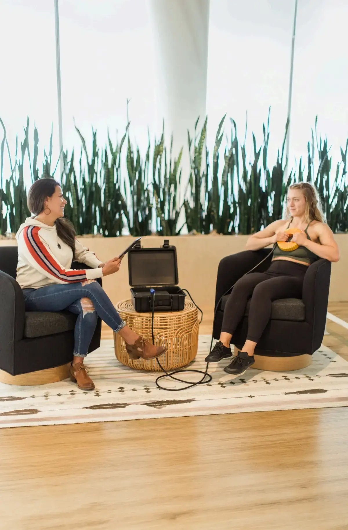 Practitioner with a tablet and a client using the AmpCoil coil in lounge chairs