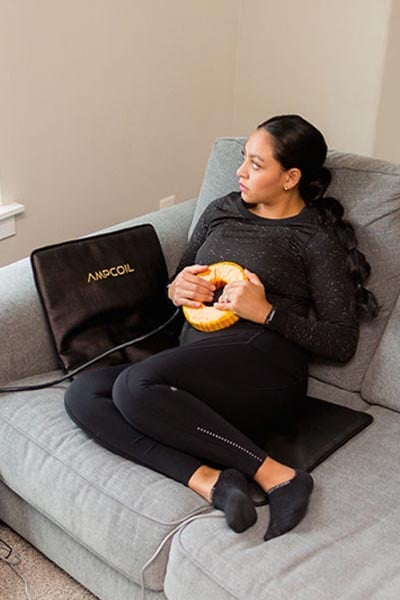woman using AmpCoil and PEMF Mat at home